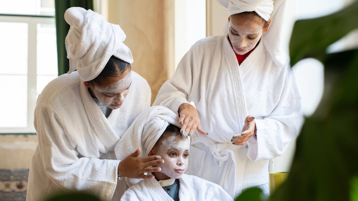 Mother and daughters enjoy a spa day at home with facial treatments and relaxation.